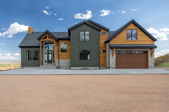 View of front of home featuring board and batten siding, stone siding, concrete driveway, and a chimney
