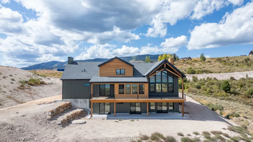 Rear view of house with a mountain view, a chimney, a sunroom, and a patio area