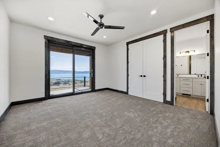 Unfurnished bedroom featuring a water and mountain view, access to outside, light carpet, ceiling fan, and recessed lighting