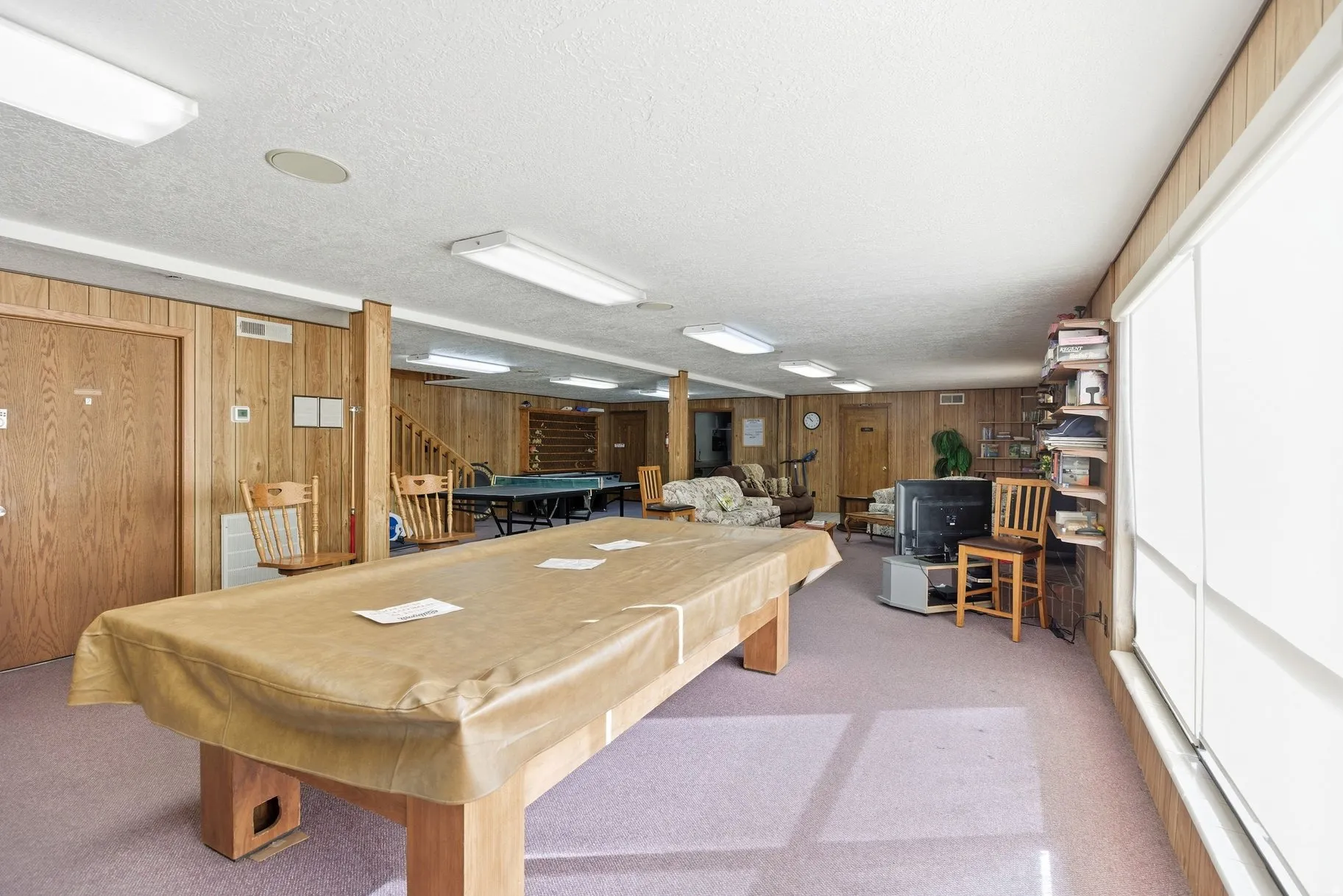 Rec room with wooden walls, light carpet, billiards table, and a textured ceiling