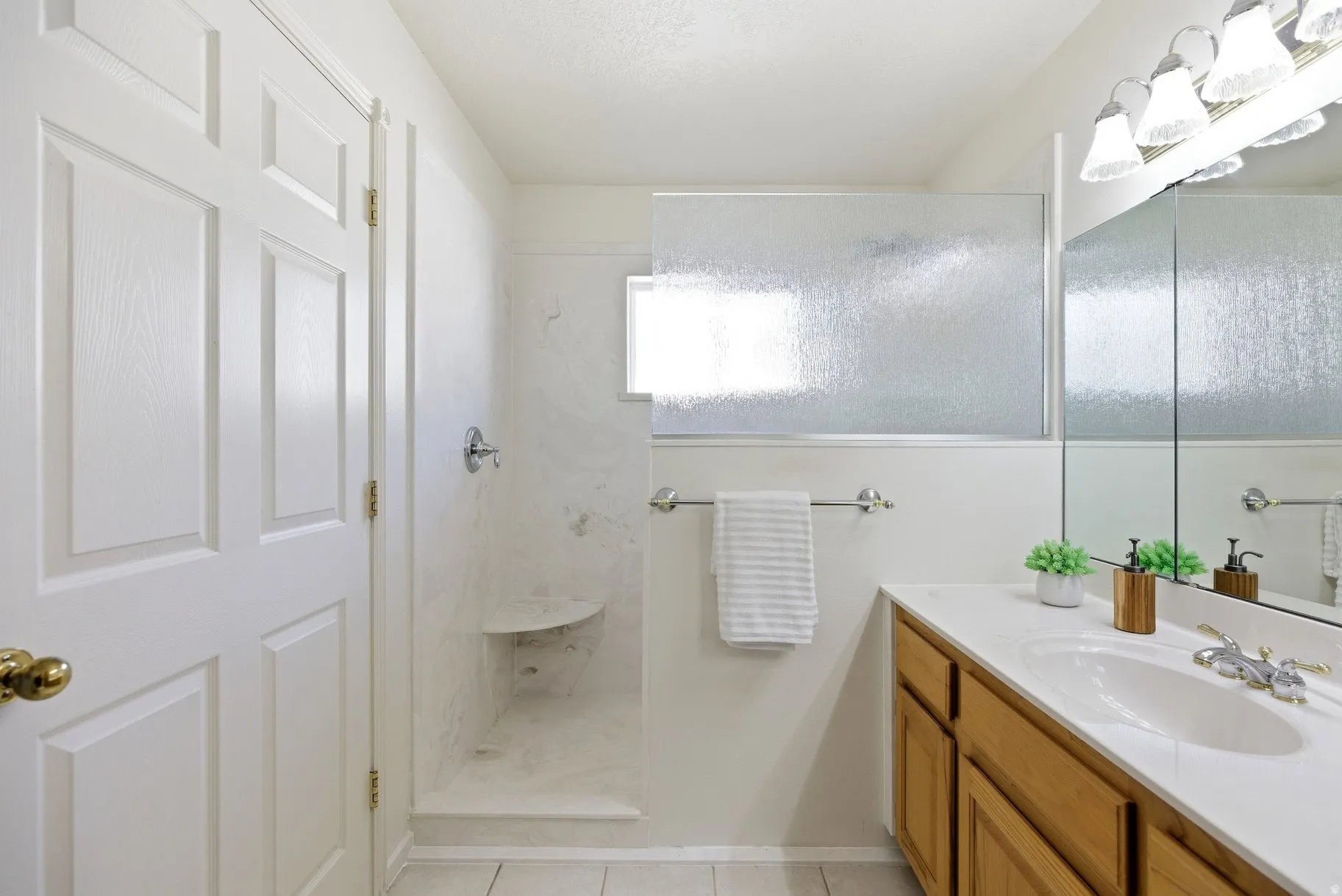Bathroom with vanity, a marble finish shower, and light tile patterned floors
