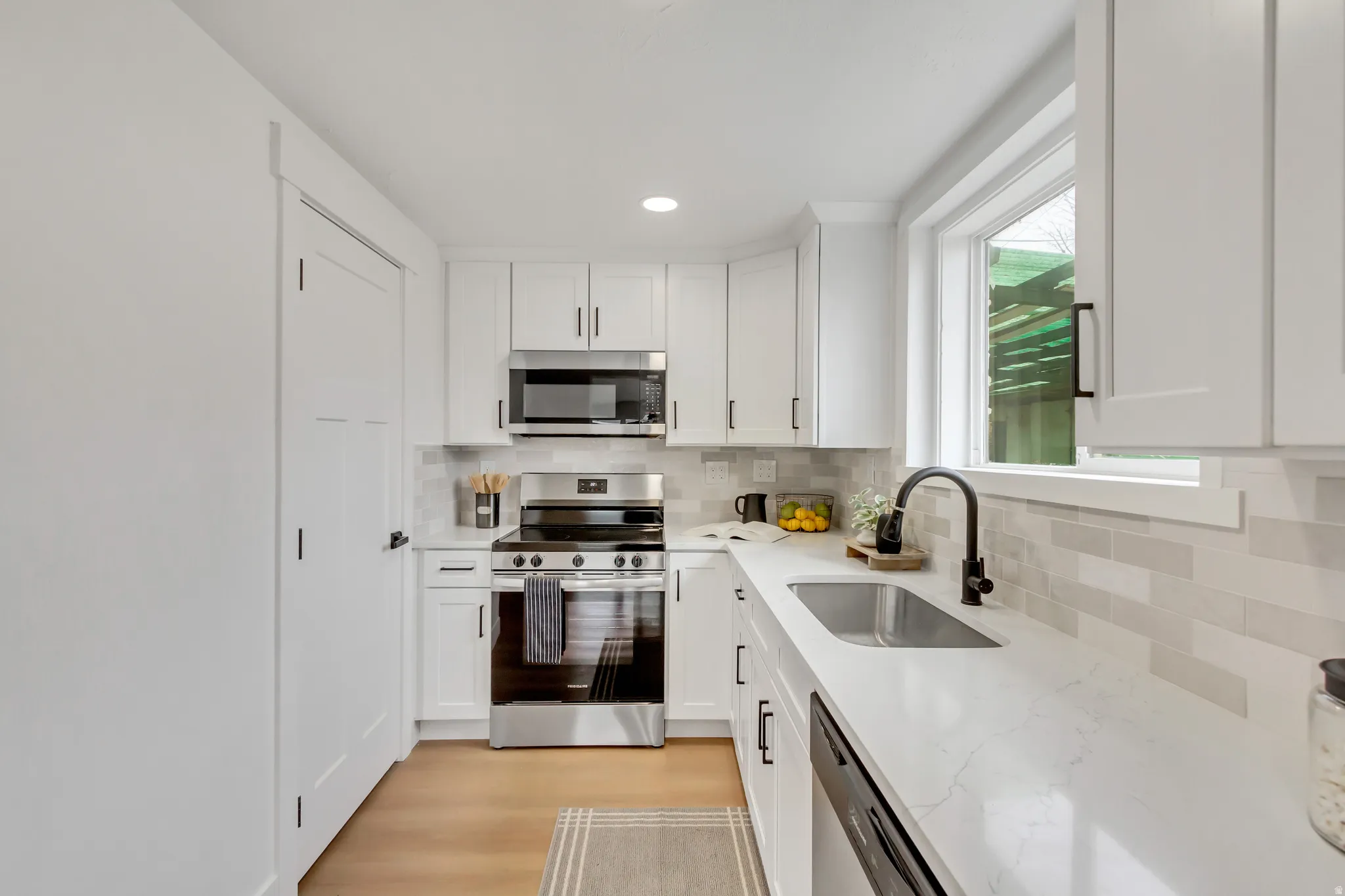 Kitchen featuring stainless steel appliances, white cabinets, light stone counters, decorative backsplash, and recessed lighting