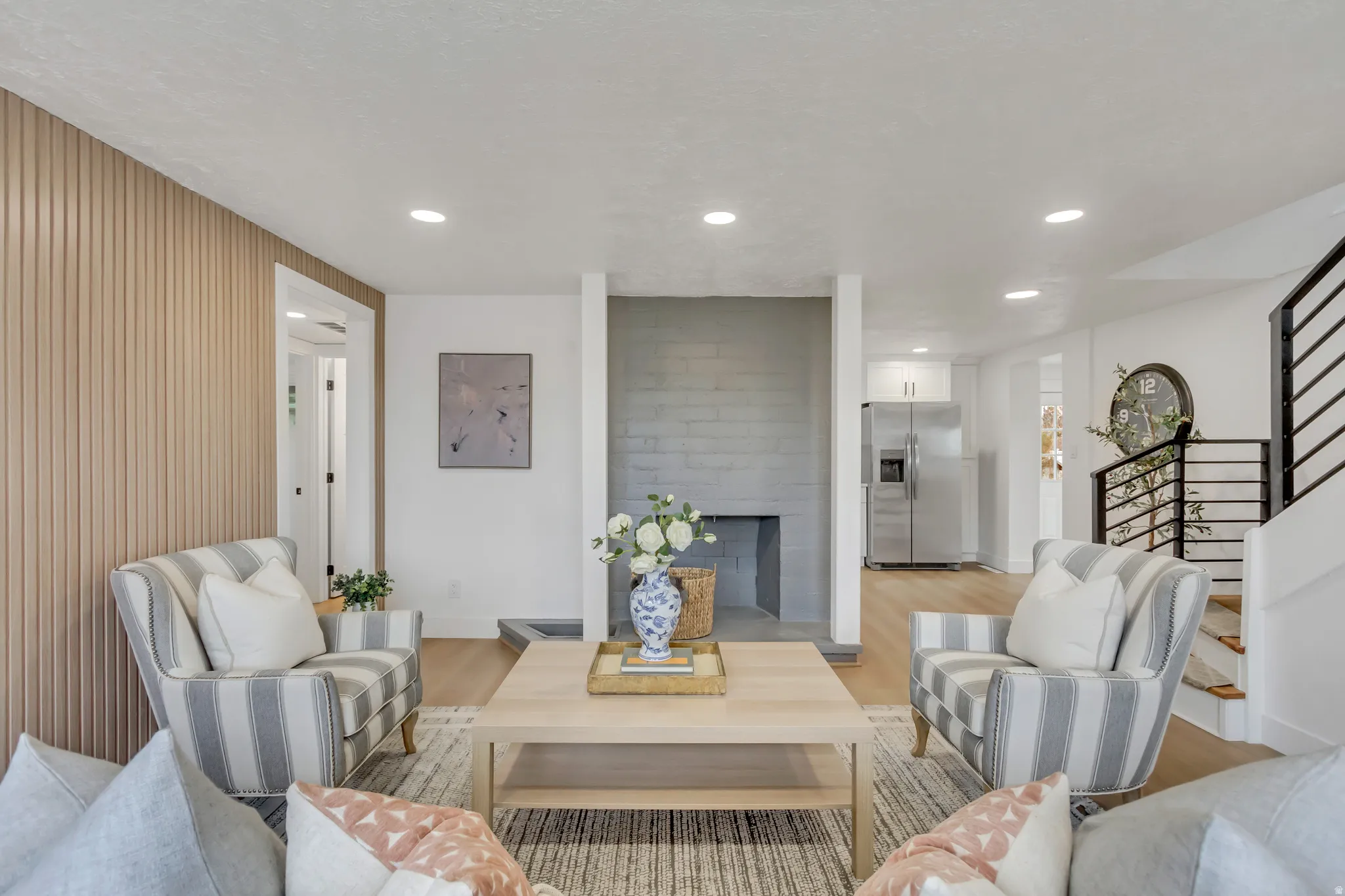 Living area featuring light wood finished floors, recessed lighting, and a fireplace with raised hearth