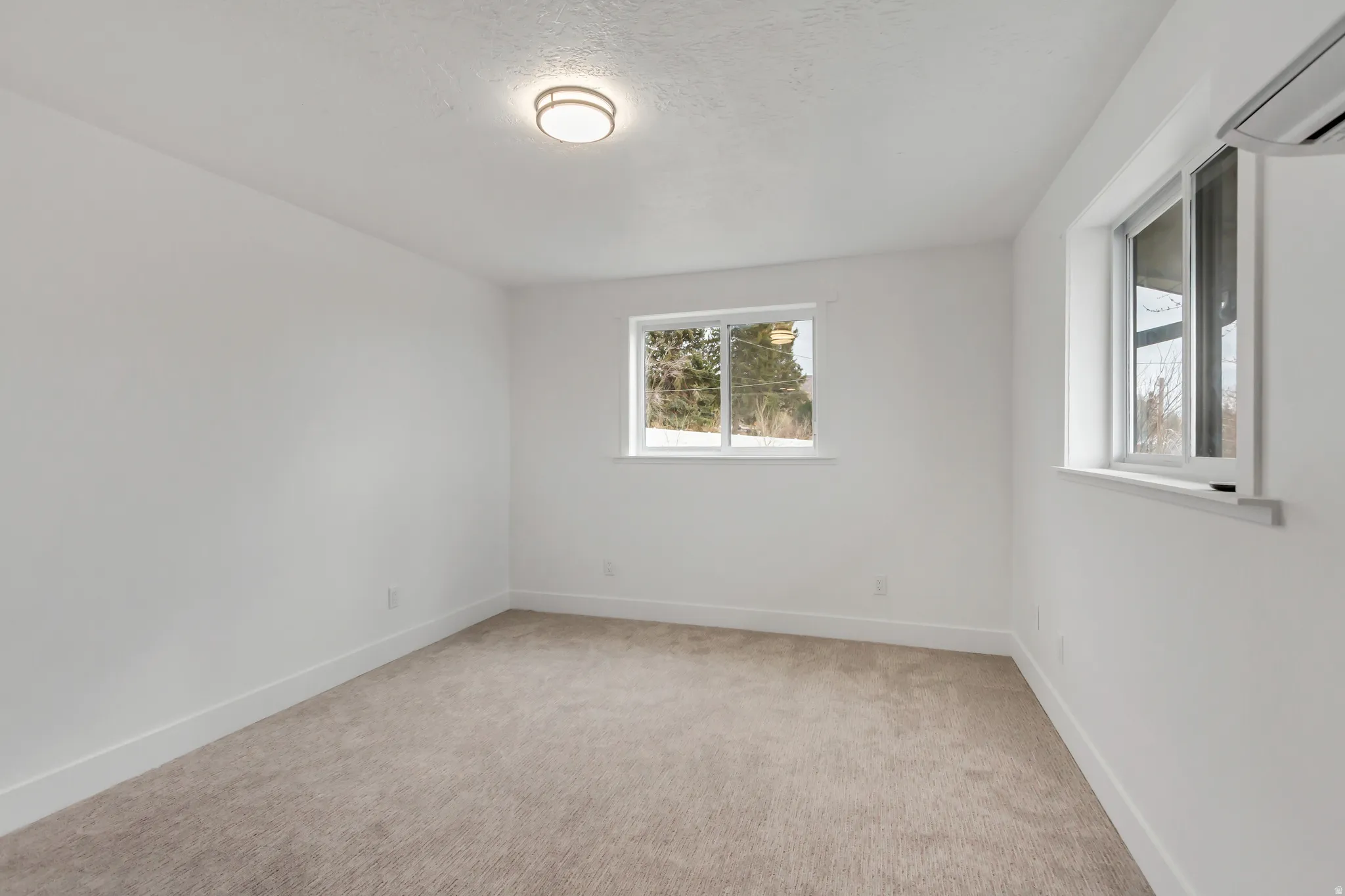 Unfurnished room with a mini split for heating / cooling and light carpet