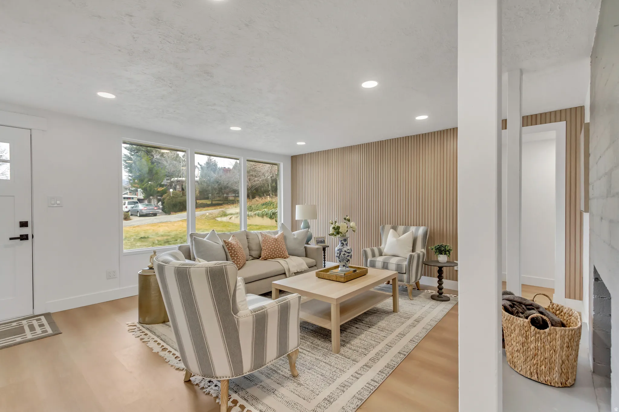 Living room featuring wallpapered walls, an accent wall, light wood-style floors, recessed lighting, and a textured ceiling