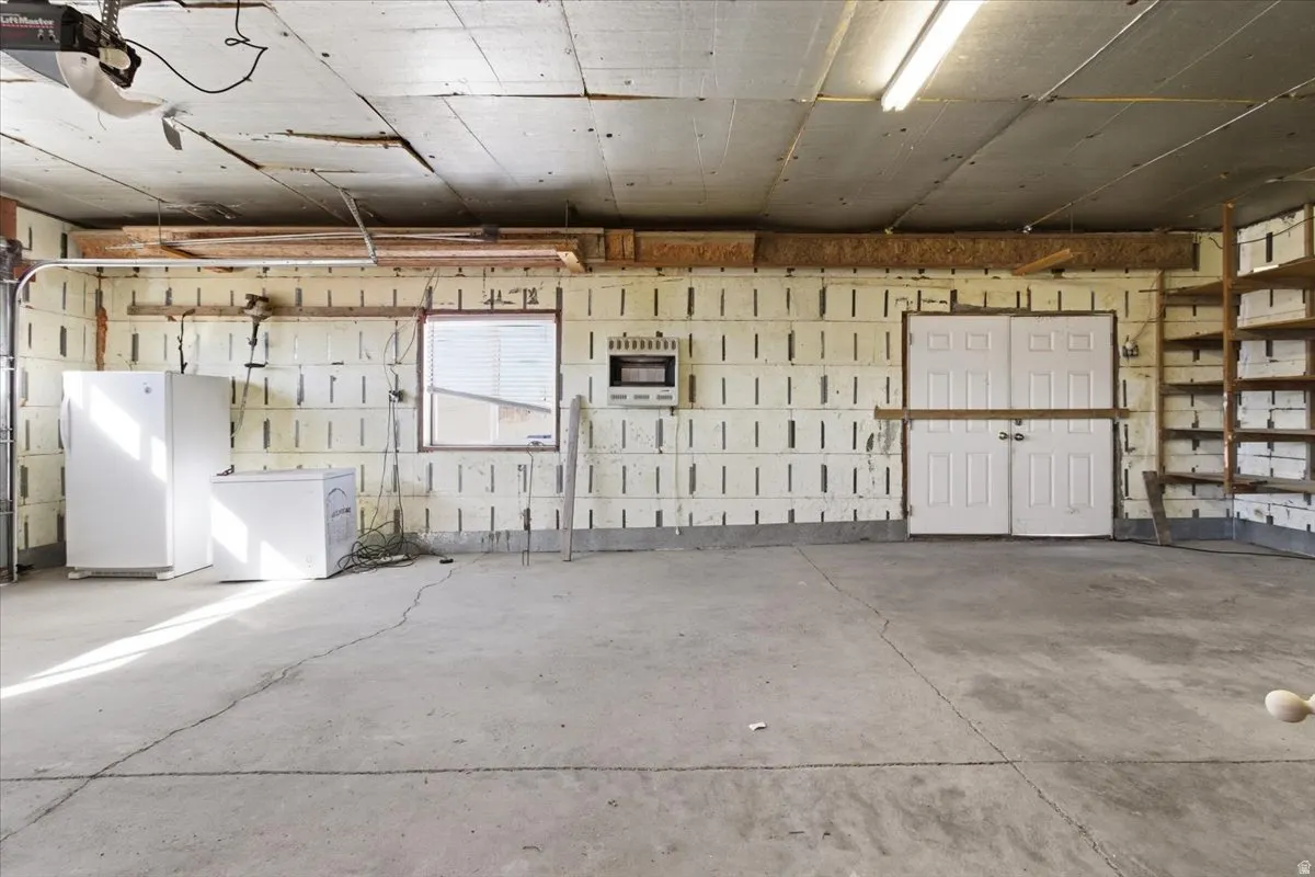 Garage featuring freestanding refrigerator, white fridge, and a garage door opener