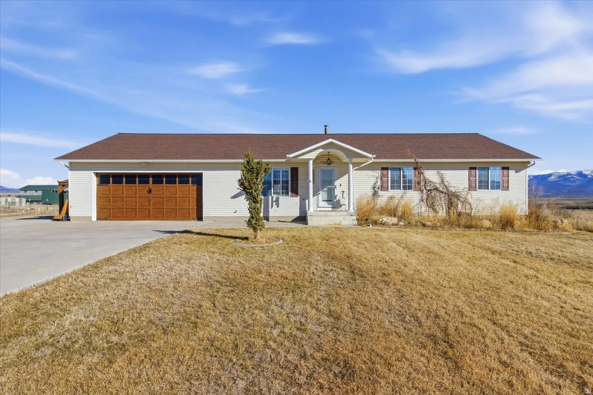 Single story home featuring a front yard, driveway, and an attached garage