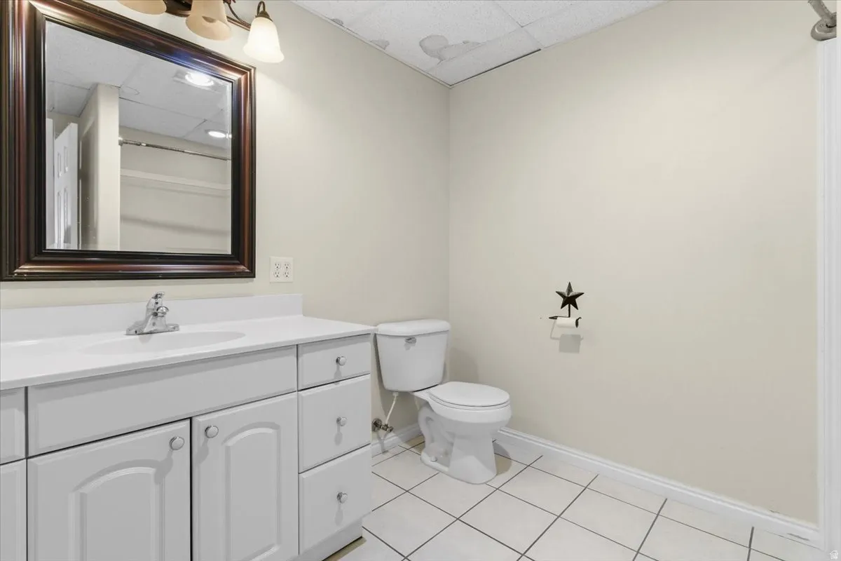 Bathroom with a paneled ceiling, vanity, and light tile patterned floors