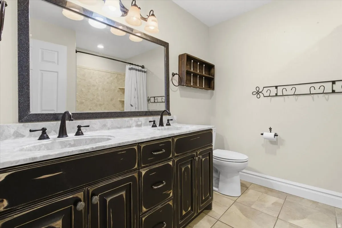 Bathroom featuring double vanity, a shower with curtain, and light tile patterned floors