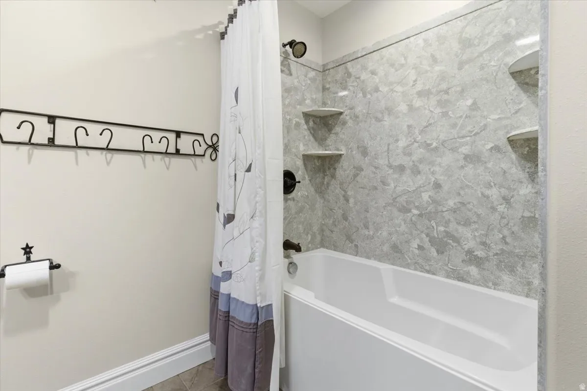 Full bathroom featuring shower / bathtub combination with curtain and tile patterned flooring