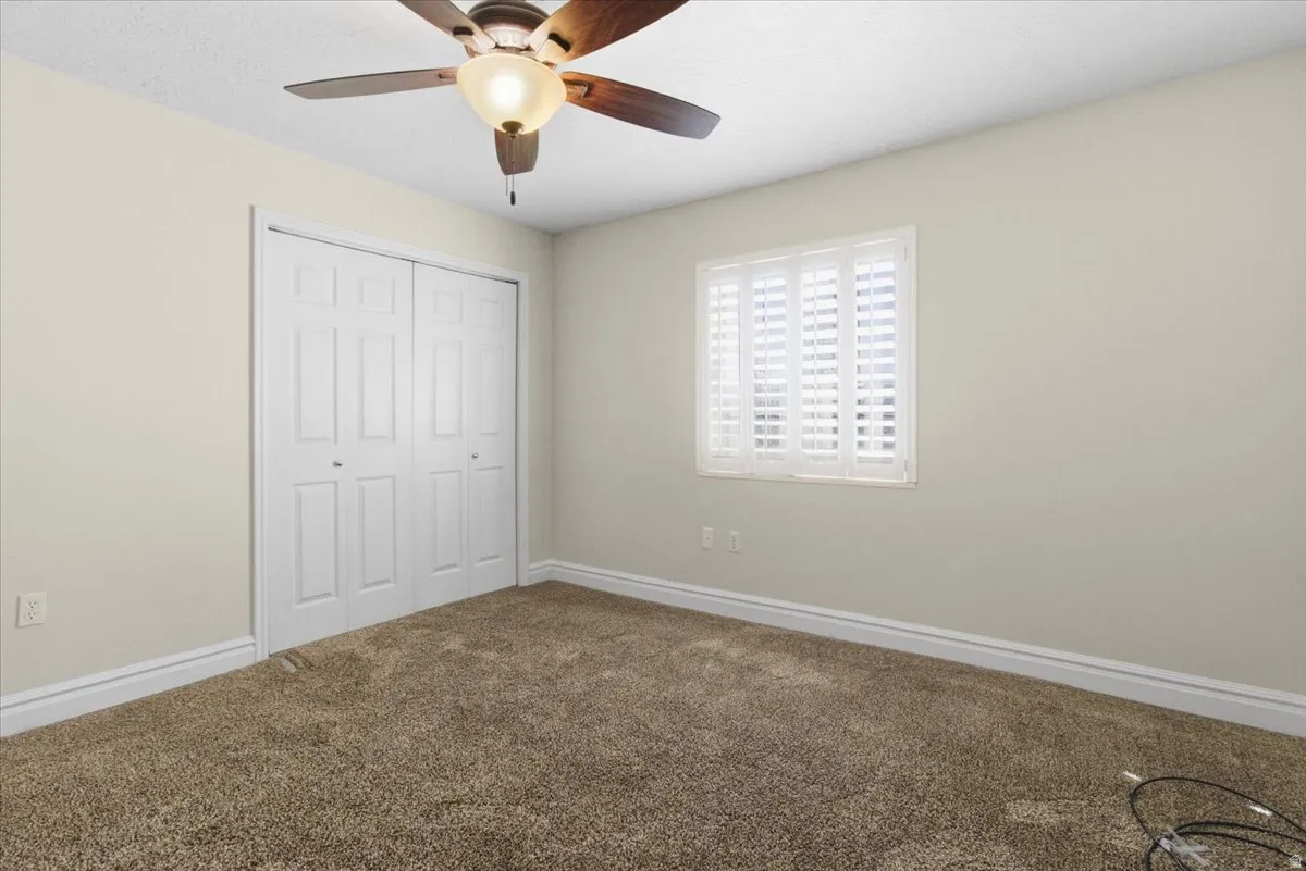 Unfurnished bedroom featuring carpet, ceiling fan, and a closet