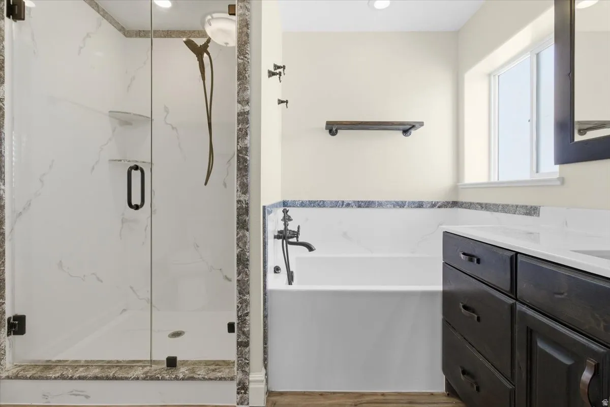 Full bathroom featuring vanity, a garden tub, and a marble finish shower