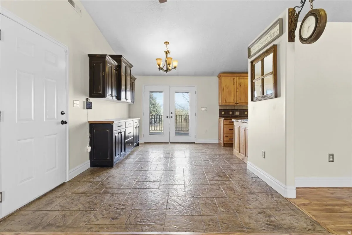 Kitchen with light countertops, stone tile flooring, french doors, hanging lights, and dark wood finish cabinetry