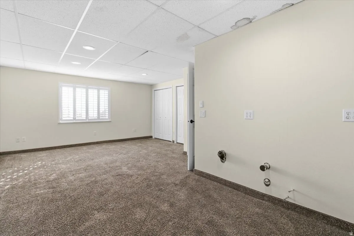 Carpeted spare room featuring a drop ceiling