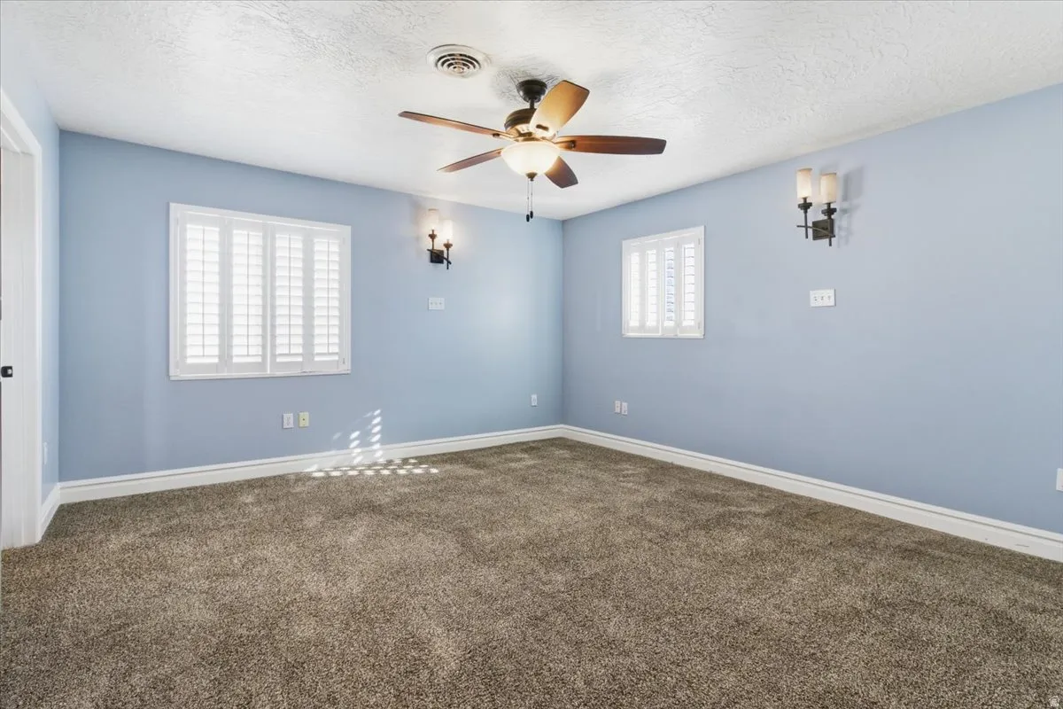 Unfurnished room featuring carpet floors, ceiling fan, and a textured ceiling