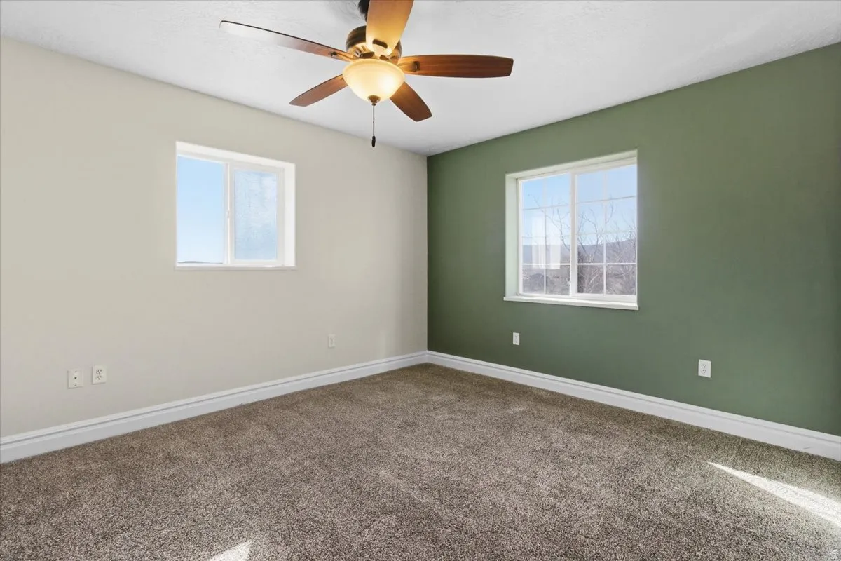 Spare room featuring carpet flooring, healthy amount of natural light, and a ceiling fan