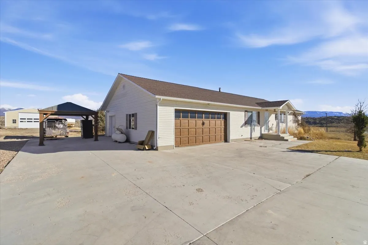View of home's exterior featuring concrete driveway, a carport, a gazebo, and a patio area