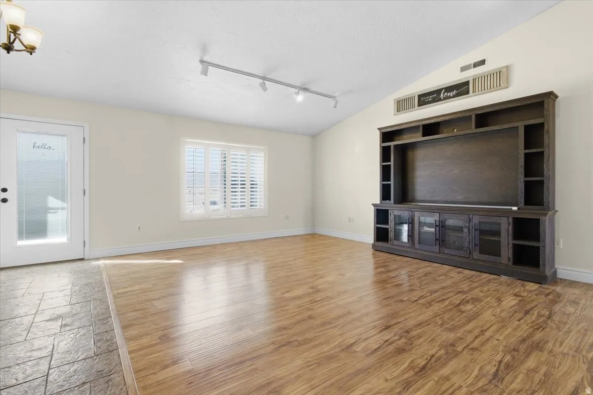 Unfurnished living room featuring track lighting, healthy amount of natural light, and light wood-type flooring