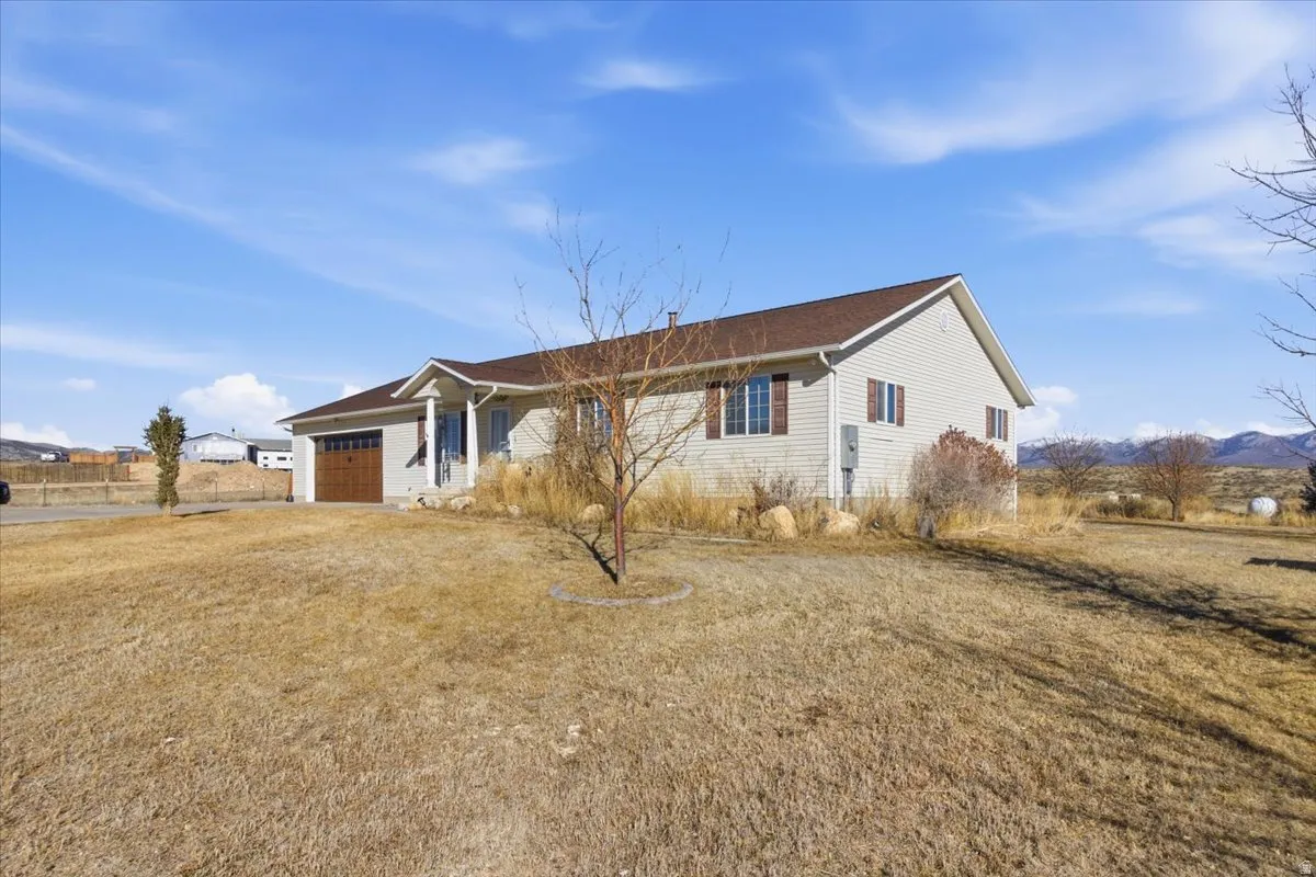 Rear view of house with an attached garage, a yard, and a mountain view