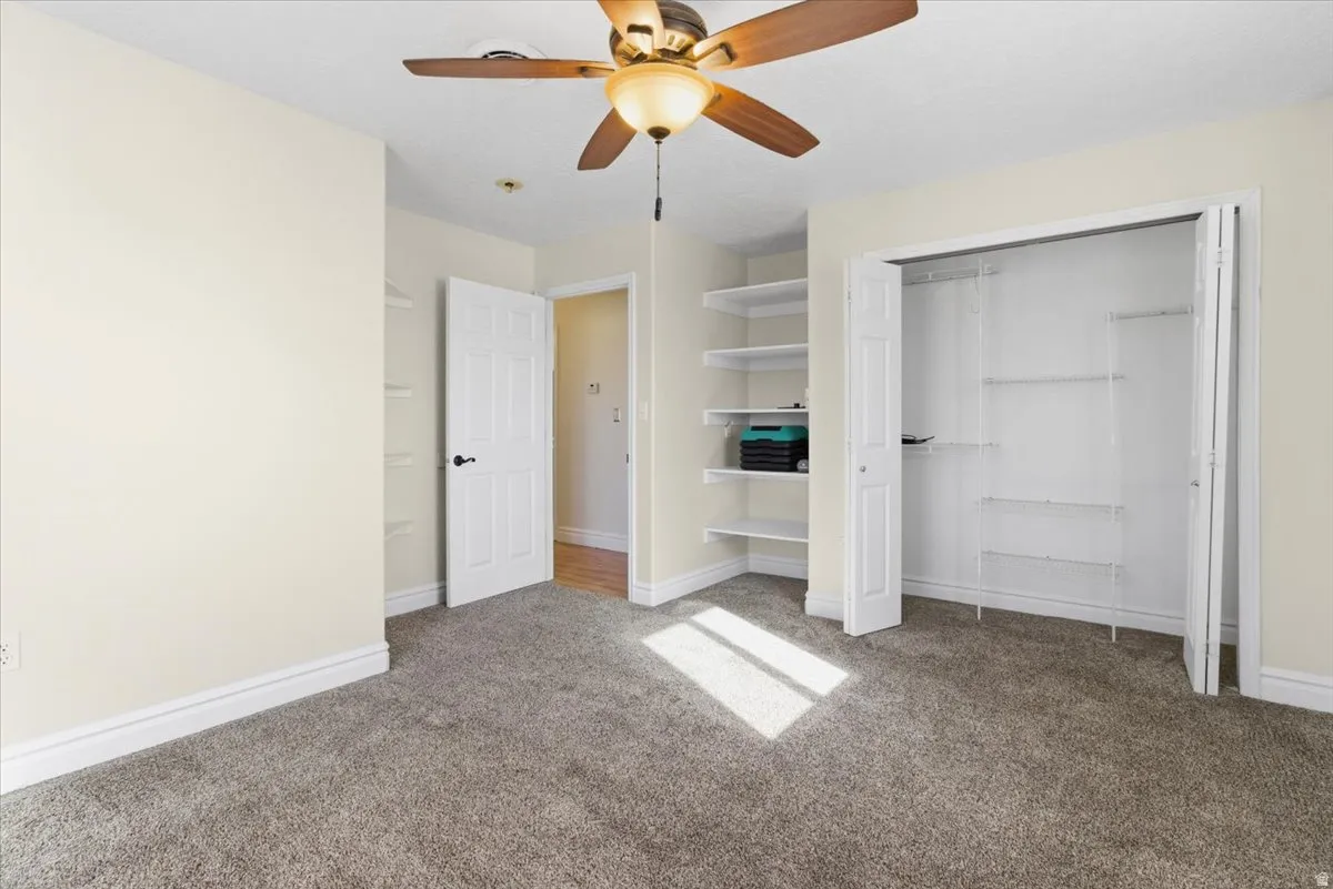 Unfurnished bedroom featuring a closet, light colored carpet, and ceiling fan