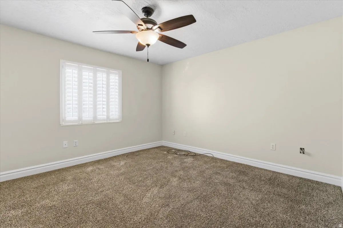 Spare room featuring carpet flooring, a textured ceiling, and ceiling fan