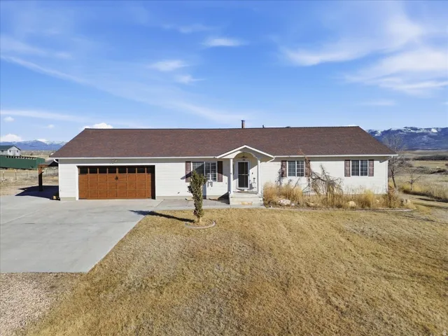 Ranch-style home with a mountain view, concrete driveway, an attached garage, and roof with shingles