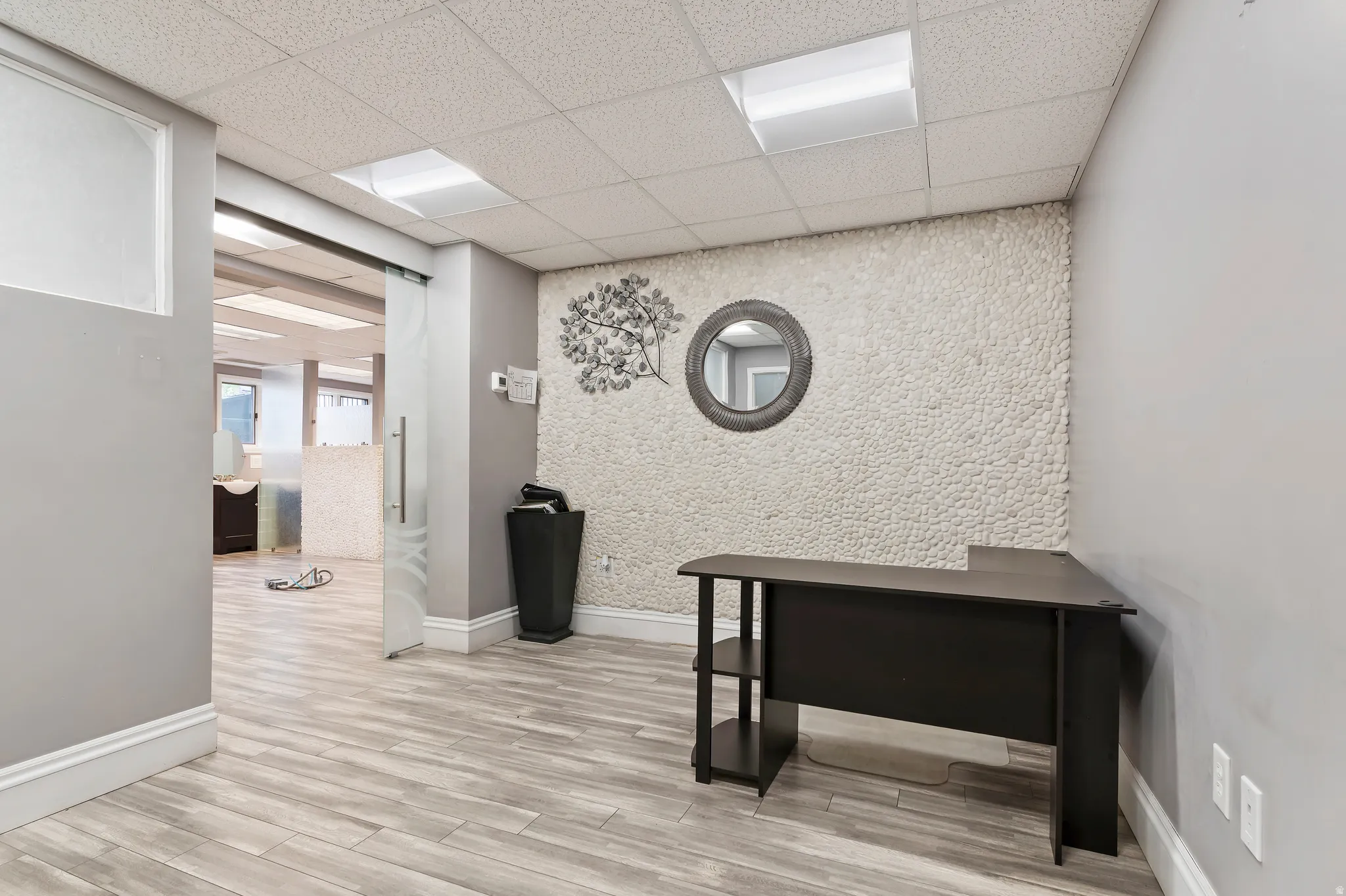 Office with an accent wall, light wood-style floors, and a paneled ceiling