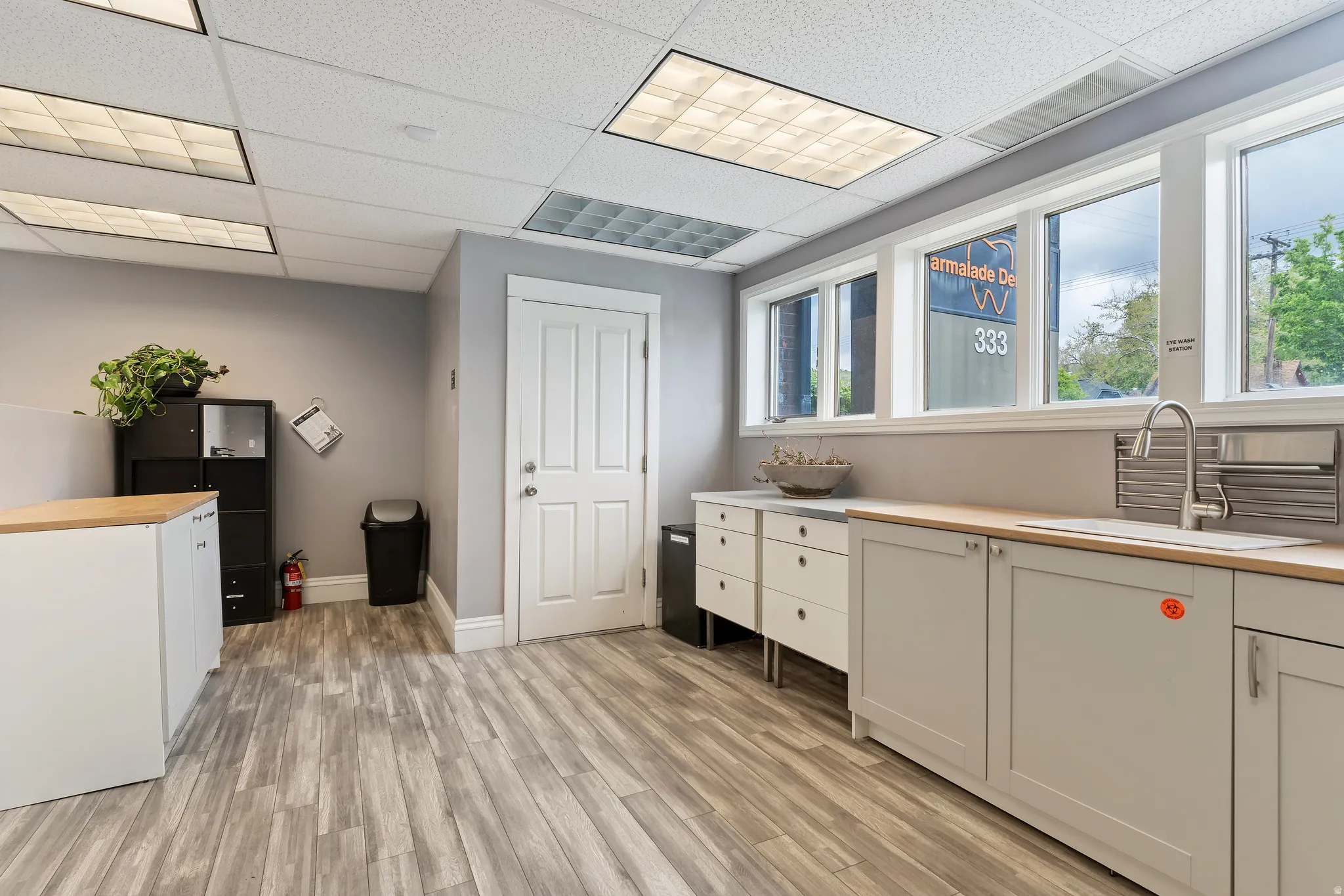 Laundry room featuring light wood-style floors and a drop ceiling