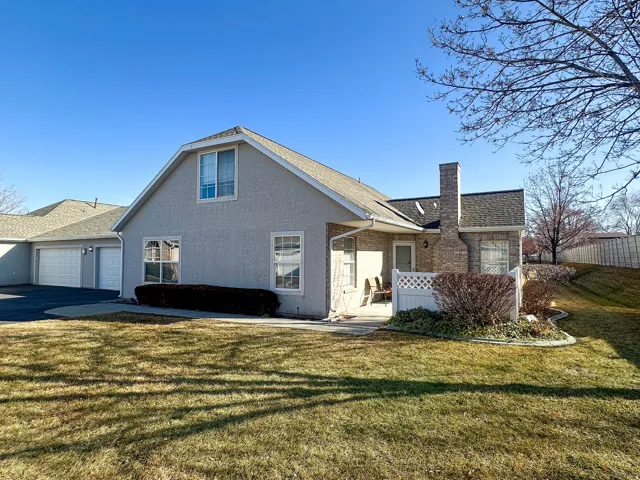 View of front of home featuring brick siding, a chimney, a shingled roof, stucco siding, and driveway