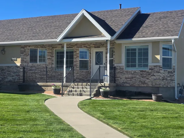 Stone veneer facade, gabled entry, asphalt shingle roof, front porch with railings, and a concrete pathway