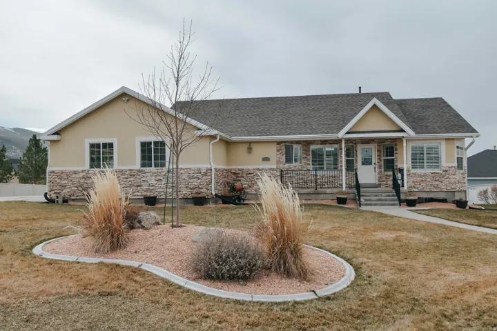 Single story home featuring stone siding, a front yard, and stucco siding