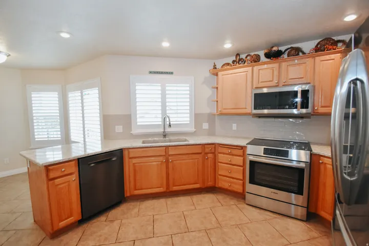 Kitchen with stainless steel appliances, backsplash, light stone countertops, and recessed lighting