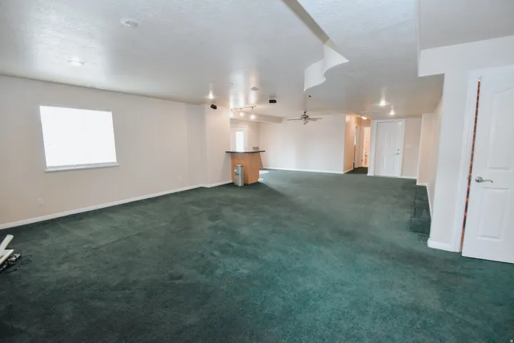 Basement with dark colored carpet, a ceiling fan, and a textured ceiling