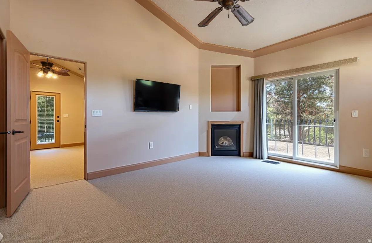 Unfurnished living room with a ceiling fan, light carpet, plenty of natural light, and lofted ceiling