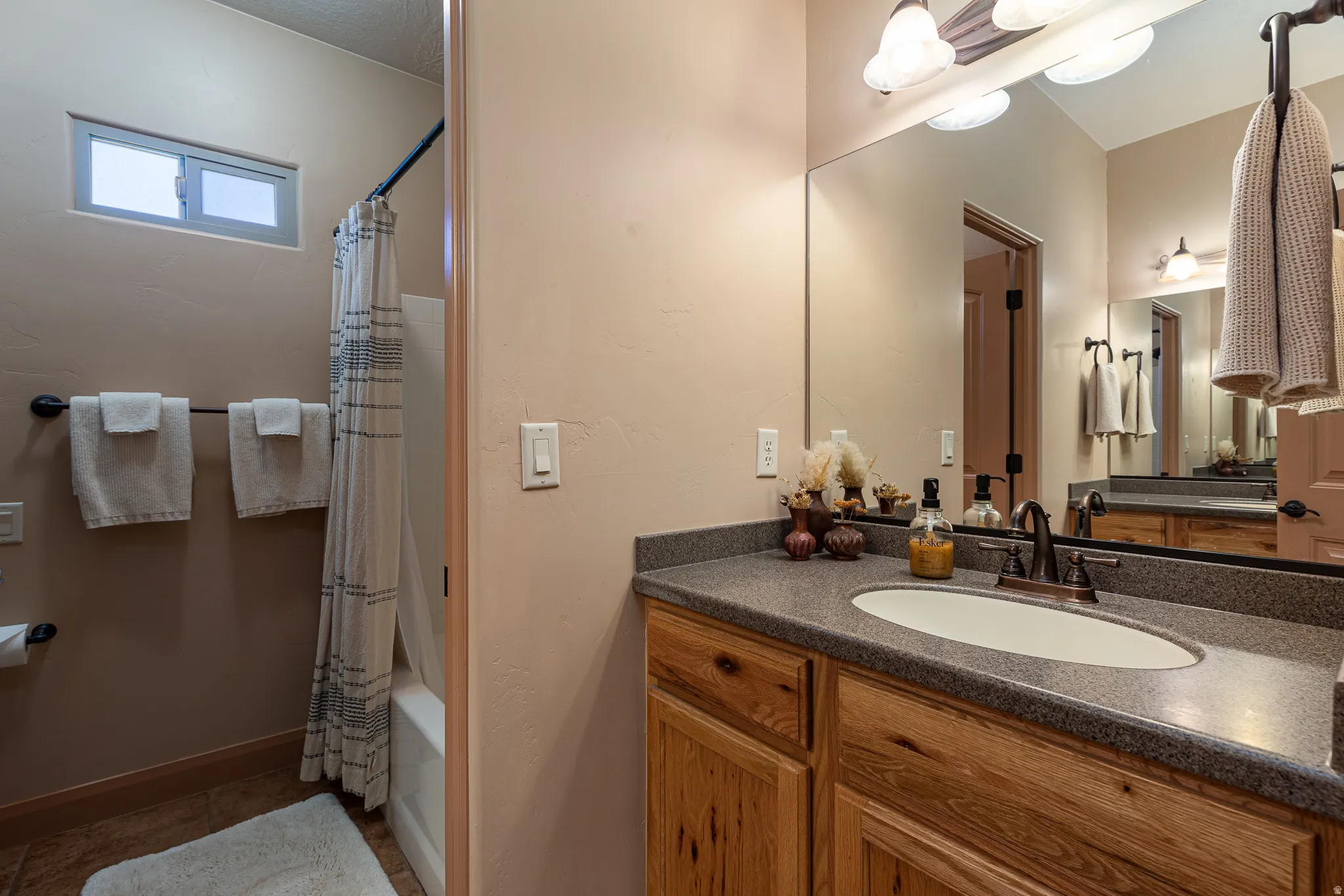 Bathroom featuring shower / bathtub combination with curtain, vanity, and dark tile patterned floors