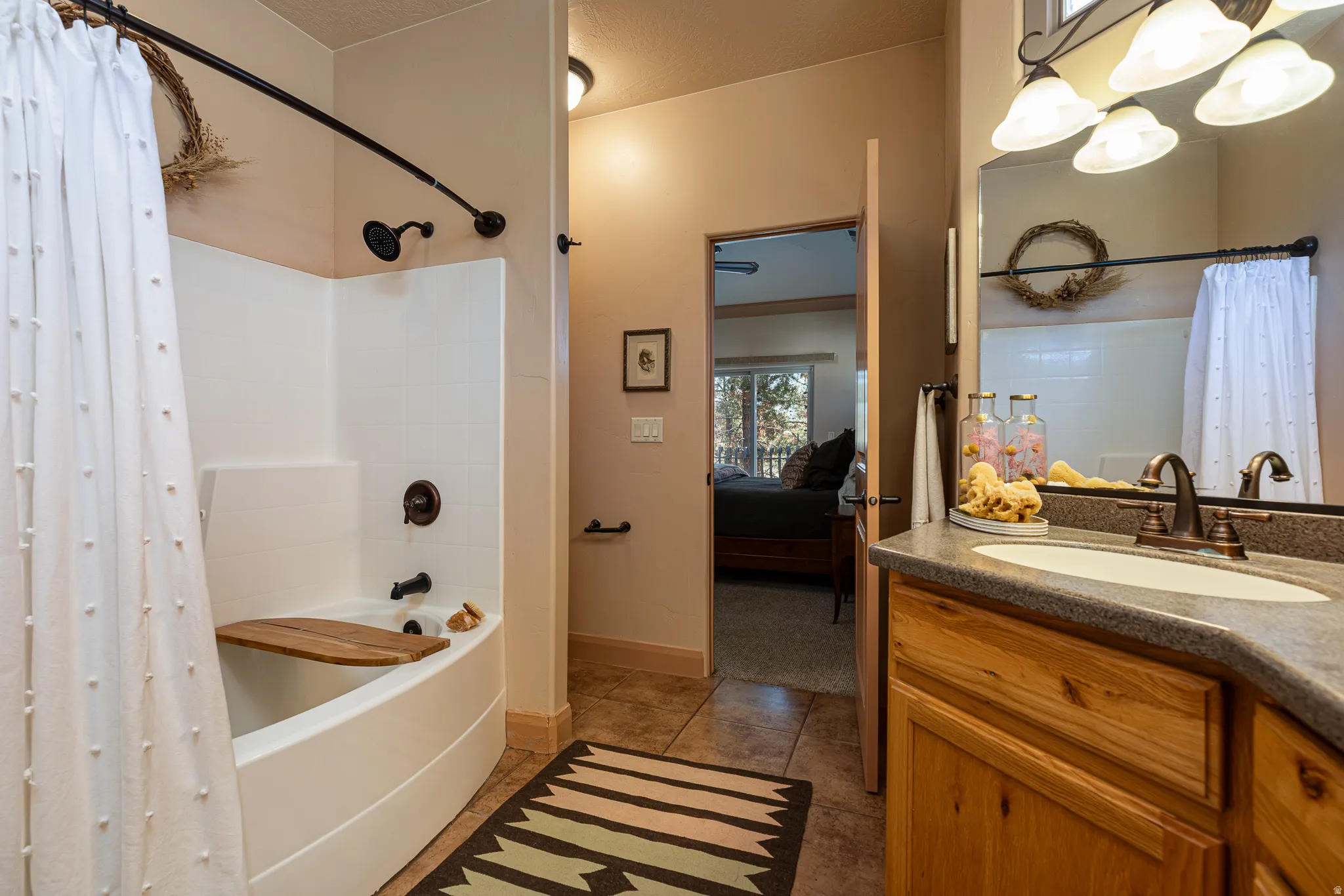 Ensuite bathroom with shower / bath combo, vanity, a textured ceiling, and dark tile patterned flooring