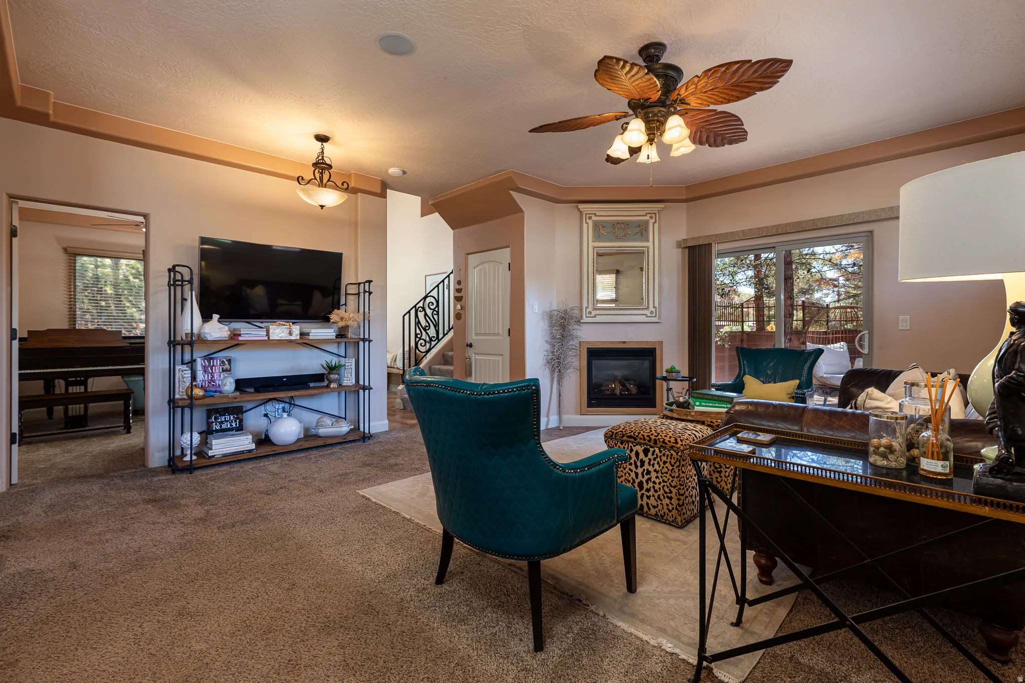 Living room with ceiling fan, healthy amount of natural light, carpet, a glass covered fireplace, and a textured ceiling