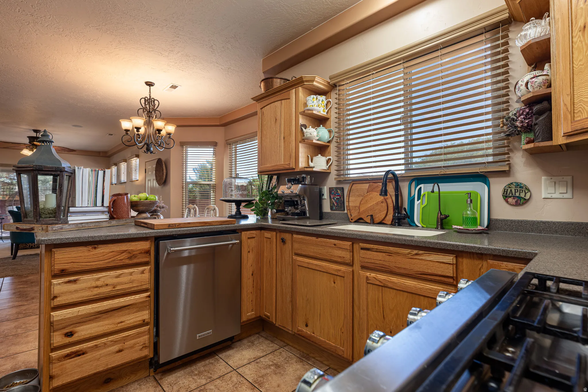 Kitchen featuring open shelves, a peninsula, dishwasher, dark countertops, and gas stovetop