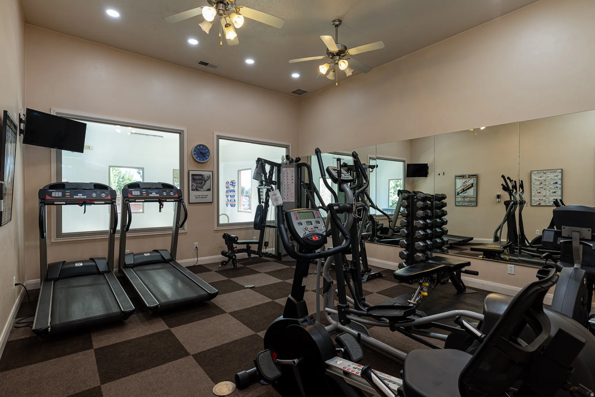 Gym featuring a ceiling fan, recessed lighting, and a high ceiling