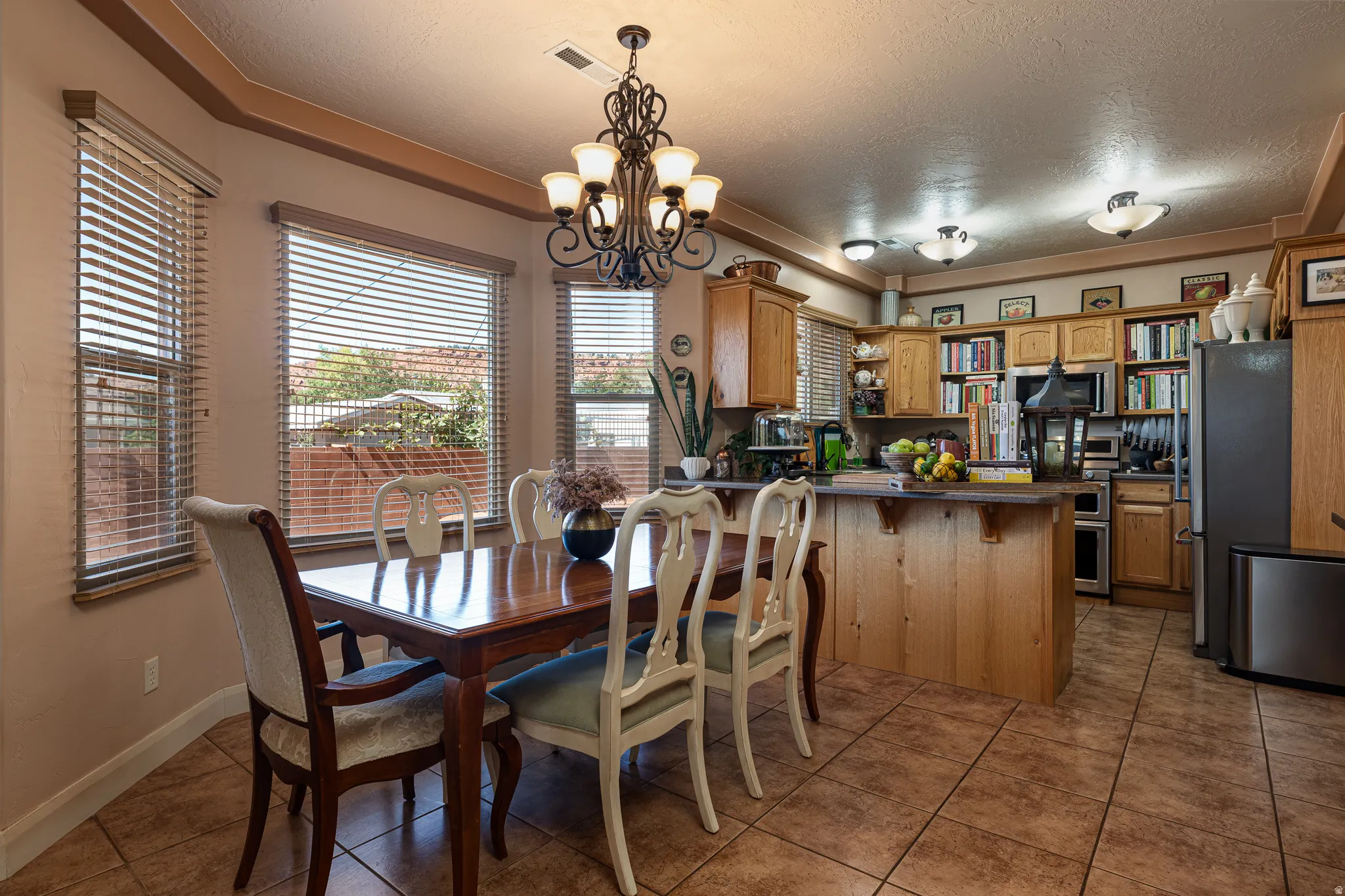 Dining space featuring hanging lights, a textured ceiling, and dark tile patterned flooring