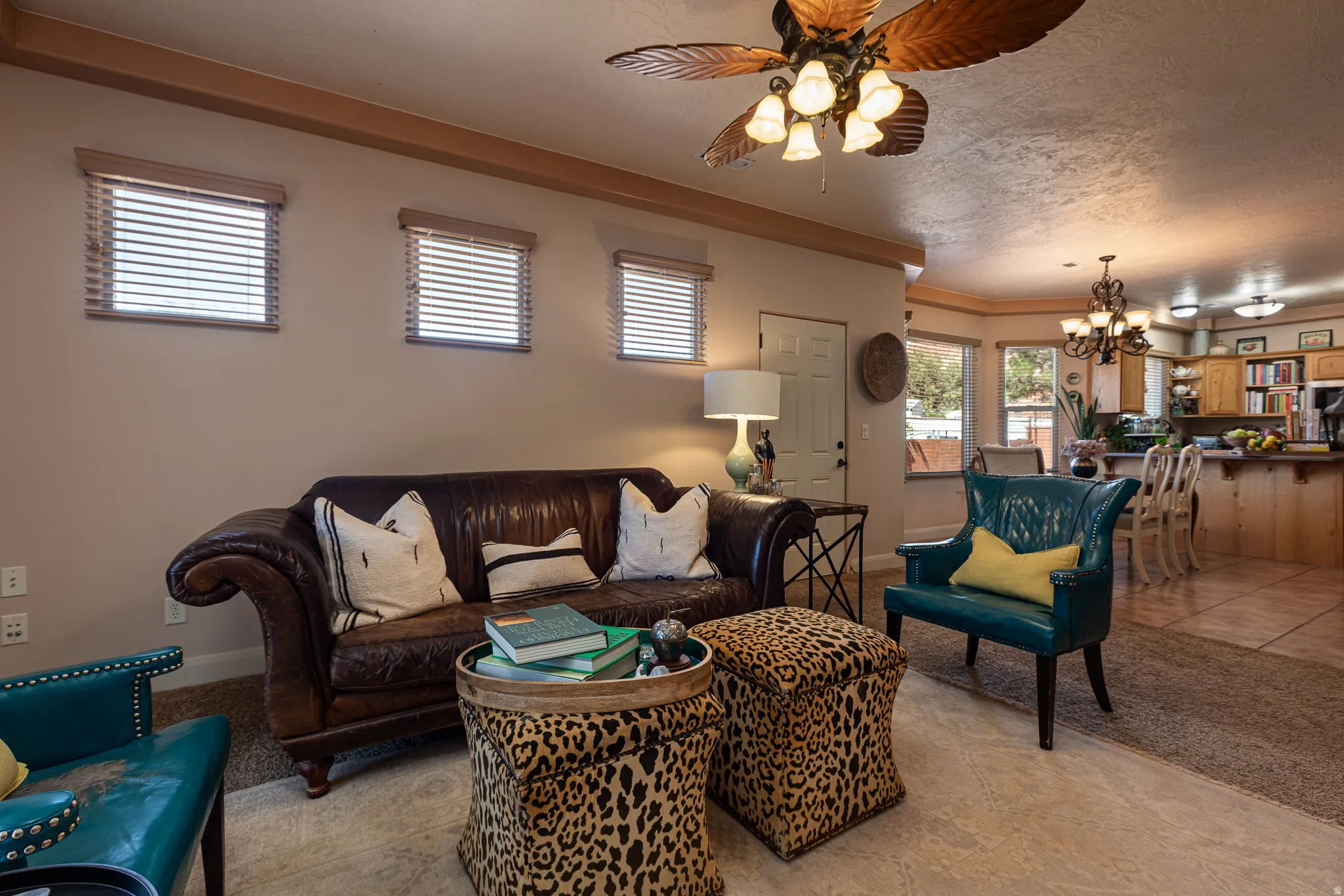 Living area with a ceiling fan, light tile patterned floors, a chandelier, and a textured ceiling