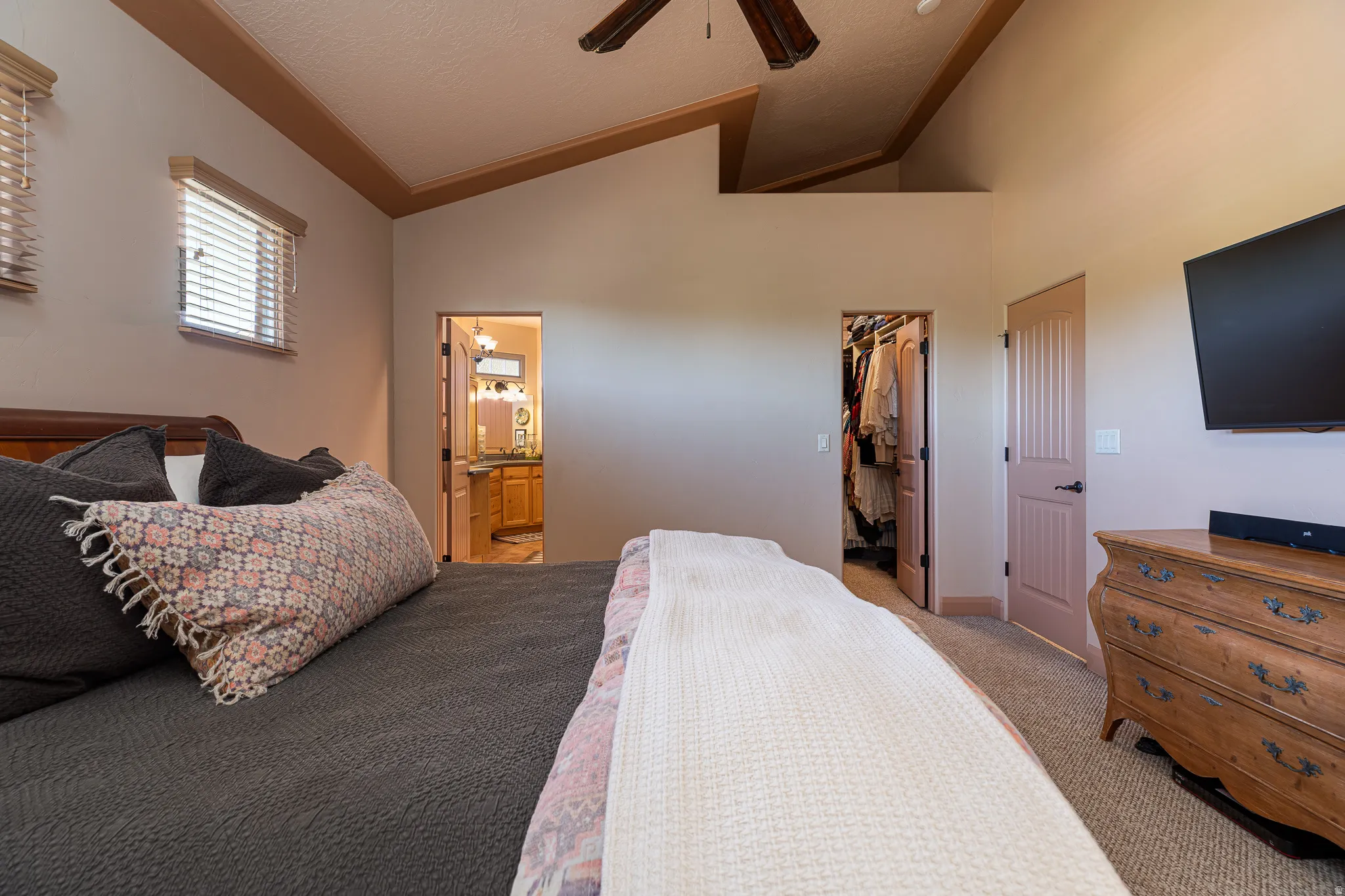 Carpeted bedroom featuring ensuite bathroom, a spacious closet, and ceiling fan