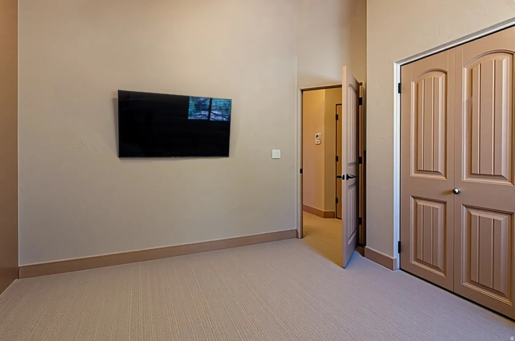 Unfurnished bedroom featuring light colored carpet, a closet, and a high ceiling