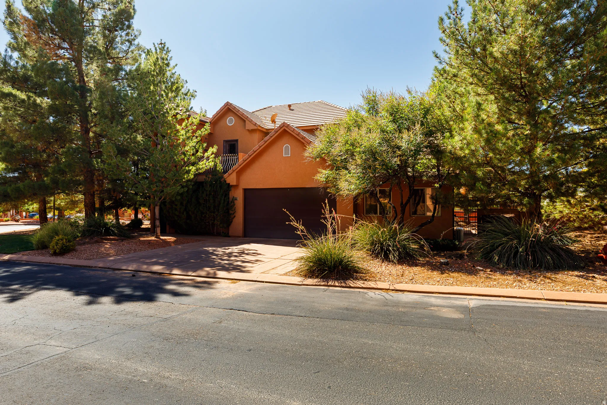 Obstructed view of property featuring driveway, stucco siding, and a tiled roof