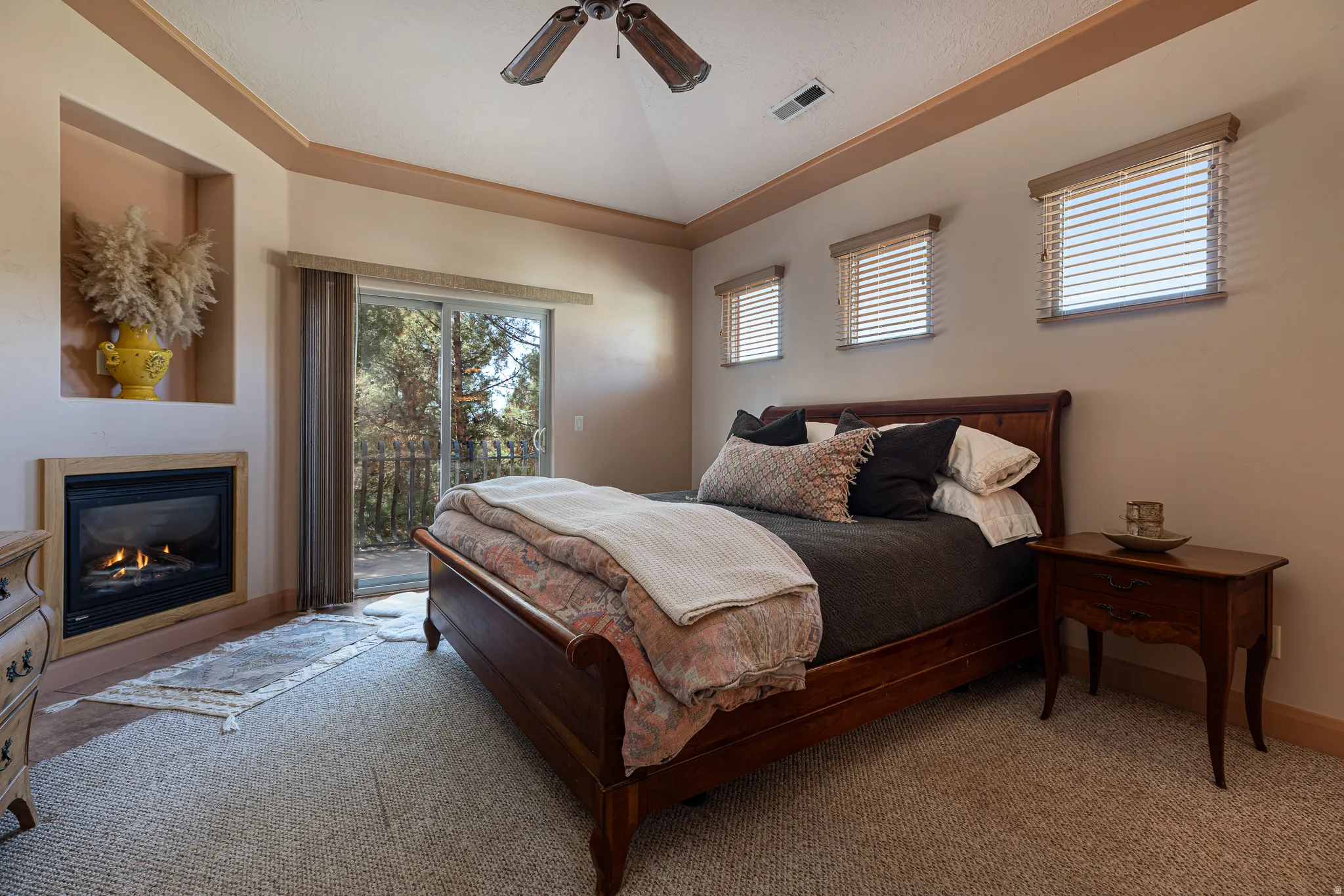 Bedroom with carpet, access to outside, a glass covered fireplace, vaulted ceiling, and ceiling fan