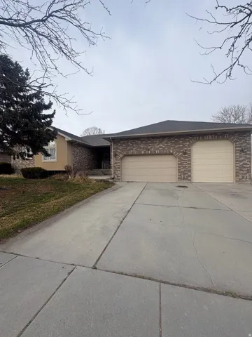 View of front facade with driveway, a front lawn, a garage, and brick siding