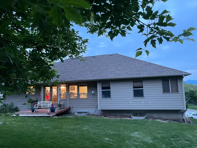 Back of property featuring a shingled roof and a yard