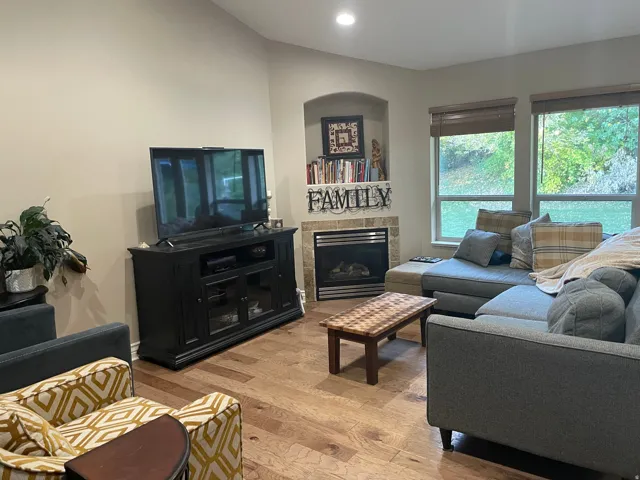 Living area featuring light wood-style floors, a tile fireplace, recessed lighting, and lofted ceiling