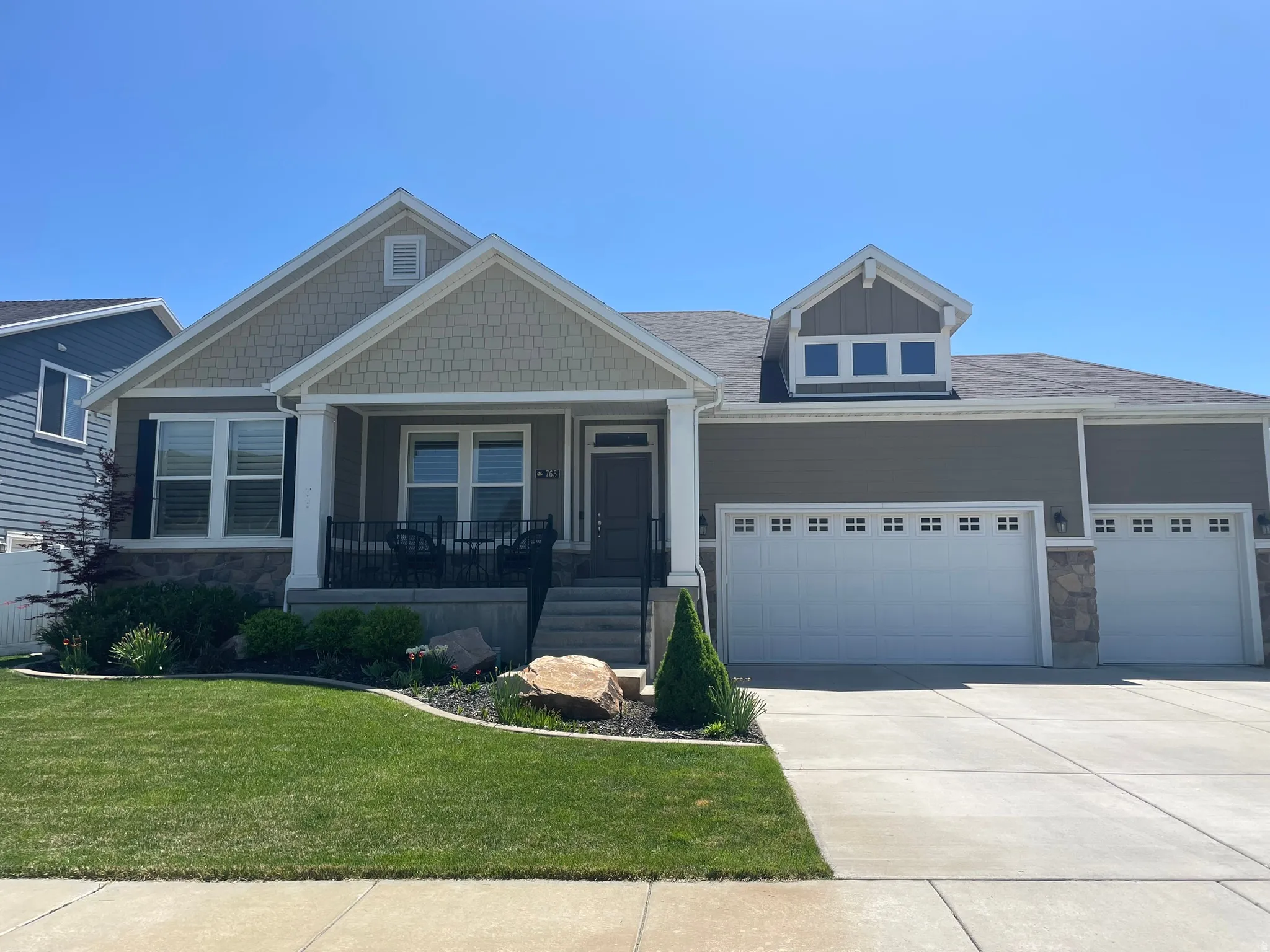 Craftsman inspired home featuring stone siding, a porch, a front lawn, and concrete driveway