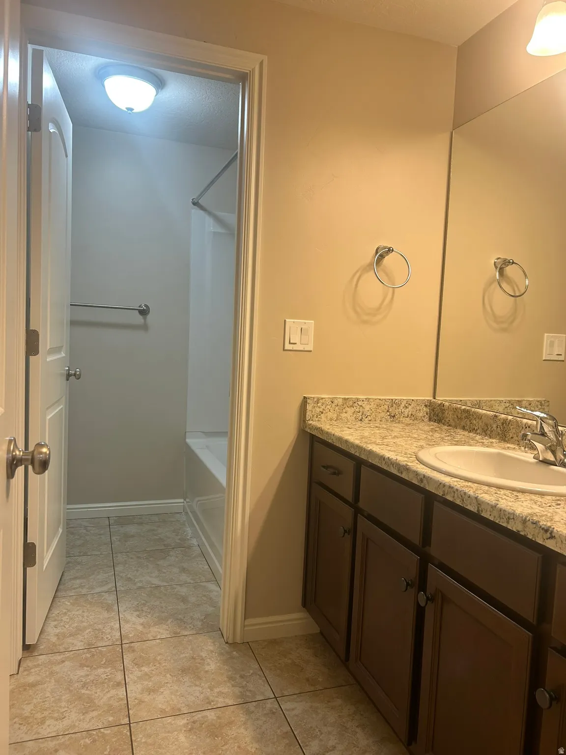 Bathroom featuring vanity, washtub / shower combination, and light tile patterned floors